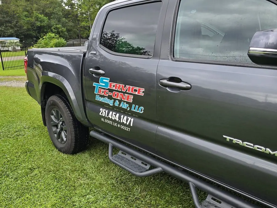 Gray pickup truck with a Service Tec One Heating & Air door decal